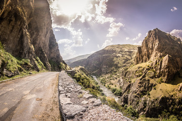View of  sunset in the beautiful mountains and rocks on the road -  Georgia, Europe.  Road trip to Georgian War Road, Caucascus Mountaints. Golden hour and picturesque view