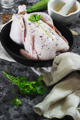 Raw chicken on a cast-iron frying pan on a black concrete background