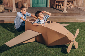 little boys playing together with handmade cardboard airplane