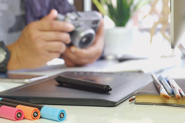 Young hipster graphic designer man using digital graphic tablet while working at modern office, professional male retoucher sitting at modern workspace with wooden table, generic design tablet
