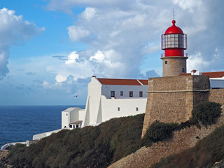Fototapeta na wymiar red lighthouse on Cabo de Sao Vicente with stone wall