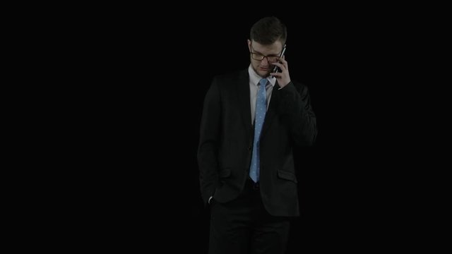 Young man in a suit walks and talks on the phone
