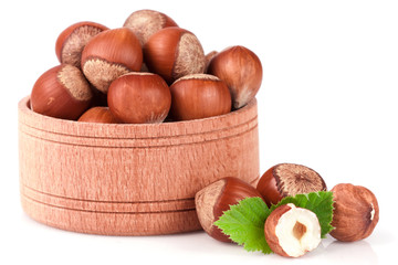 Hazelnuts with leaves in a wooden bowl isolated on white background