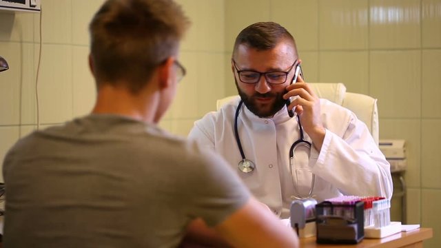 Doctor speaking on cellphone and tells good news to the patient
