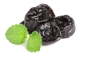 heap of dried plums or prunes with a mint leaf isolated on white background