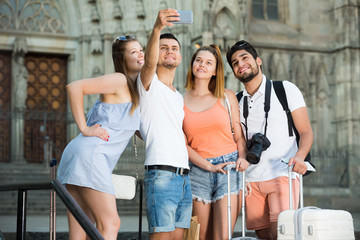 Four young travellers smiling and making selfie