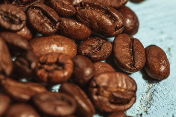 Dark many roasted coffee beans on blue background