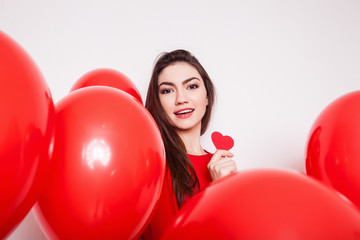 Beautiful brunette girl holds Paper red heart on a white background