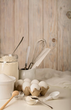 Kitchen utensils and tools for homemade baking on a light wooden background.