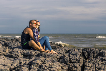 Portrait of young and happy couple sitting on the rocks next to the sea. France.