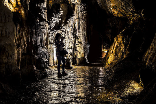 Portrait of woman walking in stalactite caves. Beautiful silhouette and light. France.