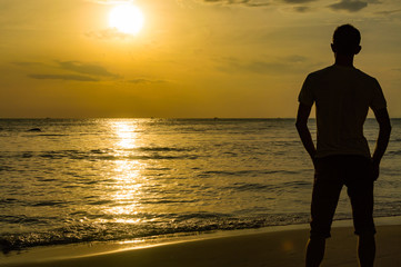 Fototapeta premium Silhouette of young man on the beach in golden sunset