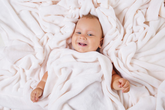 Cute smiling baby under towel after bath