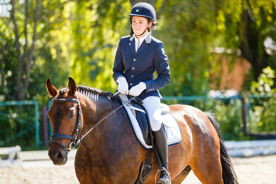 Young rider girl on bay horse at dressage equestrian competition