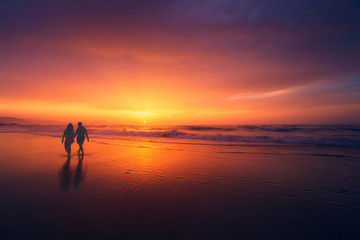 couple marchant sur la plage au coucher du soleil