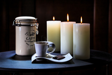 Cup of coffee costs on a table on a background of burning candles