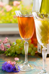 Cold summer wines, white and rose, served in beautiful glasses on the fresh air, outdoor in the green garden with flowers, sunny day