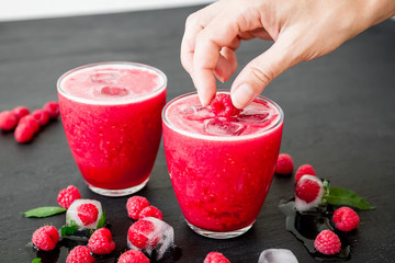 Raspberry ice cold refreshing cocktail with berries on dark background
