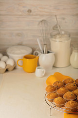 Kitchen utensils, tools and products for the capcake (muffins) on a light wooden background.
