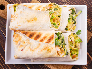 Chicken, avocado, cilantro and cheese burritos. View from above, top studio shot