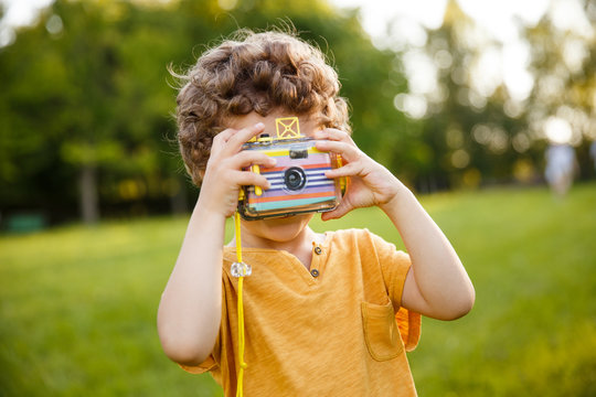 Young Boy Holding Camera Standing In Park