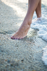 Close up of woman legs walking on the beach.