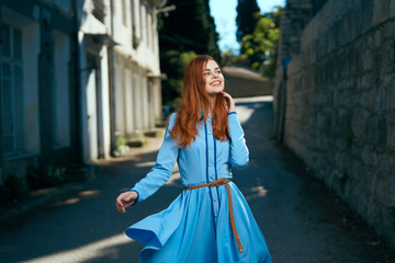 Young beautiful woman in a blue dress walking along a street in the city