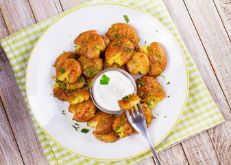 Smashed Potatoes with parsley, dried rosemary, lemon zest and yogurt sauce. View from above, top studio shot
