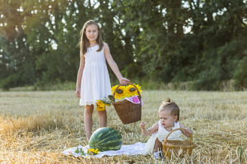 Young happy children  on the field, behind haystack, having picnic . Summer vacation.