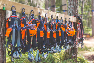 Climbing equipment in summer adventure park camp. Helmets and harnesses hanging on a board ready for extreme three forest exploration. Concept for summer adventures family time team building vacation.
