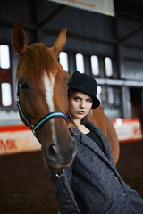 Beautiful girl in hat stay with a horse