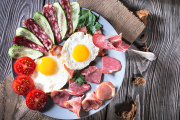 Fried eggs with bacon and vegetables on a wooden table