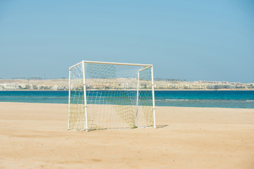 Soccer goal post with white net standing on coastline