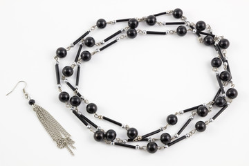 Set earrings and black pearl necklace chain isolated on white background.