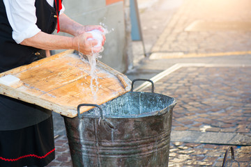 Elderly woman washes the laundry with bucket and wooden board as she once did