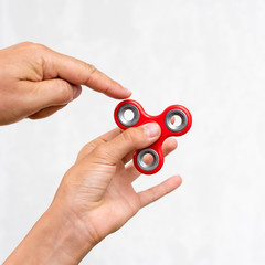 Fidget spinner. Red hand spinner, boys playing with fidgeting hand toy. Stress relief. Anti stress and relaxation adhd attention fad boy concept.