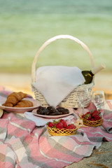 Fototapeta na wymiar Summer time at the sea. Romantic picnic on the beach - wine, strawberries and sweets.