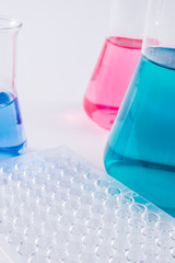  research, science and clinic background. 96 well micro plate and  laboratory beakers with colorful liquids and reagents.  