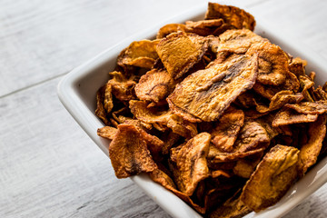 Dried Carrot Chips on white wooden surface.
