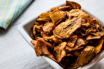 Dried Carrot Chips on white wooden surface.
