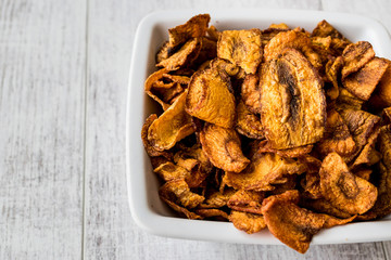 Dried Carrot Chips on white wooden surface.