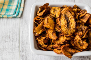 Dried Carrot Chips on white wooden surface.