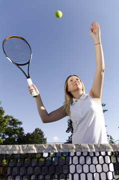 Beautiful young woman, tennis player is going to smash the ball on net 