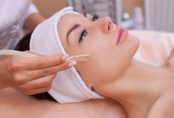 The doctor-cosmetologist makes the face vacuum therapy on the cheek of a beautiful, young woman in a beauty salon.Cosmetology and professional skin care.