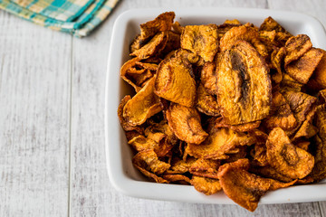 Dried Carrot Chips on white wooden surface.