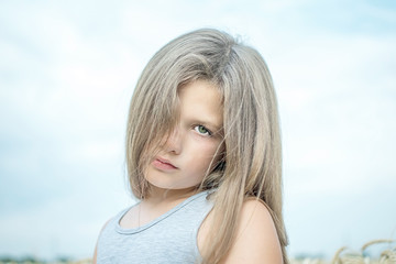 A pretty little girl looking sad in the background of blue sky