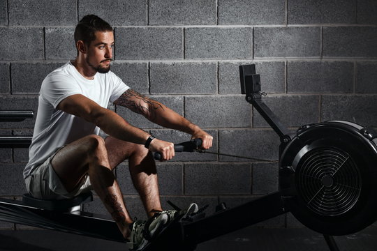 Fitness Young Man Using Rowing Machine In The Gym