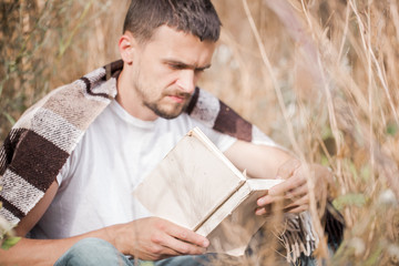 Fototapeta premium a young man on the field reading a book