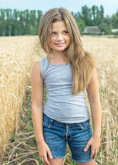 sexy little girl with long hair posing in wheat field at a summer day