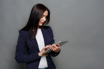Concentrated woman with tablet on gray background